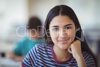 Portrait of happy schoolgirl sitting in classroom