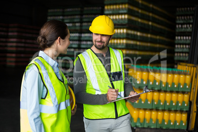 Factory workers discussing inventory over clipboard