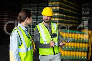Factory workers discussing inventory over clipboard