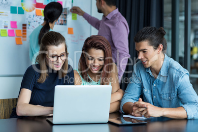 Businesspeople having discussion over laptop in office