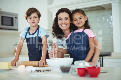 Mother and kids mixing the dough while preparing cookies