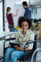 Portrait of smiling disabled business executive in wheelchair using digital tablet