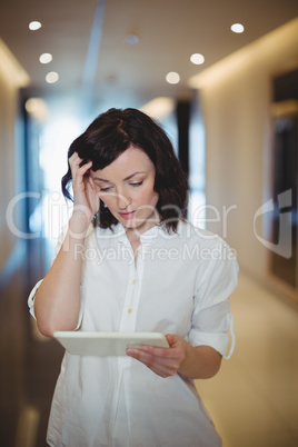 Female executive using digital tablet in corridor