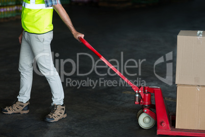 Factory worker pulling trolley of cardboard boxes