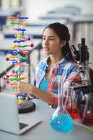 Attentive schoolgirl experimenting molecule model in laboratory