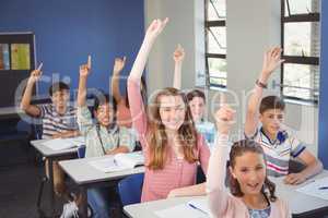 School kids raising hand in classroom at school