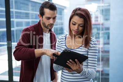 Man and woman discussing over digital tablet