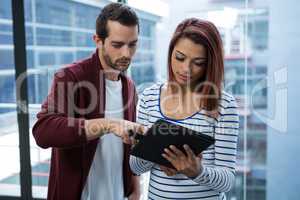 Man and woman discussing over digital tablet