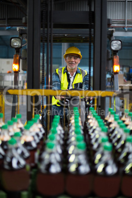 Portrait of smiling factory worker driving forklift