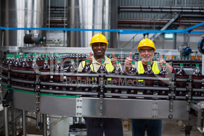 Factory workers showing their thumbs up at drinks production line