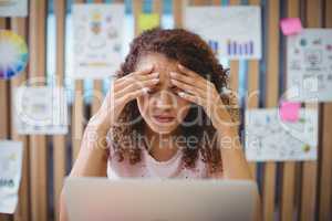 Frustrated female graphic designer with laptop siting at desk