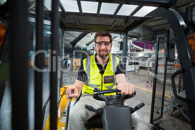 Portrait of smiling factory worker driving forklift