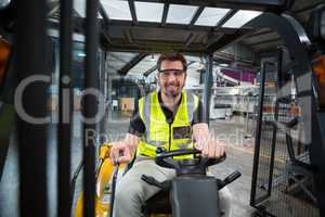 Portrait of smiling factory worker driving forklift