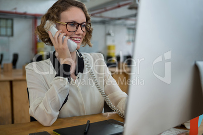 Woman talking on landline phone at desk