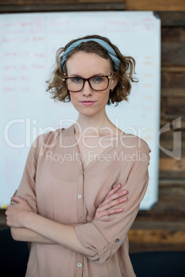 Female business executive standing with arms crossed in office