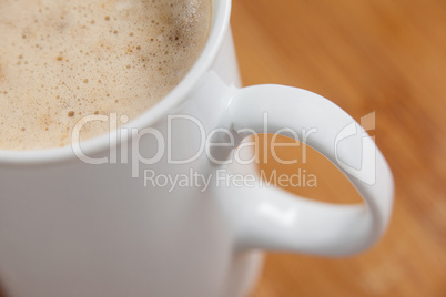 Close-up of white mug of coffee with creamy froth