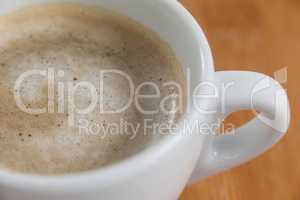 Close-up of white coffee cup with creamy froth