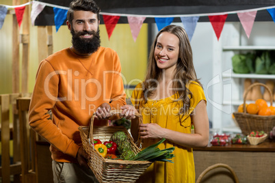 Man and woman holding a basket of vegetables at the grocery store