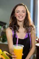 Smiling shop assistant offering the juice at the counter