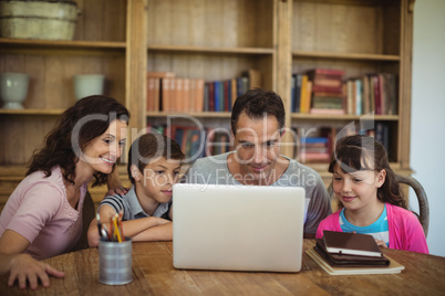 Parents and kids using laptop on table in study room