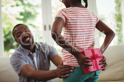 Daughter hiding gift behind her back for father