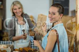 Female customer receiving a parcel from bakery staff at counter