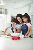 Mother and kids mixing the dough while preparing cookies