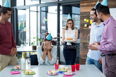 Businesspeople giving surprise birthday party to colleague