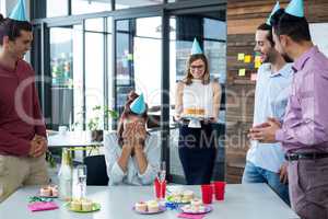 Businesspeople giving surprise birthday party to colleague