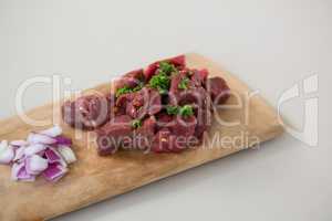Minced beef and chopped onions on wooden tray