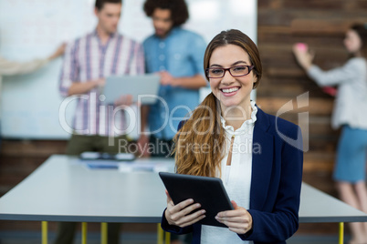 Portrait of female business executive with digital tablet sitting in office