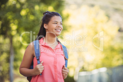 Smiling schoolgirl standing with schoolbag in campus