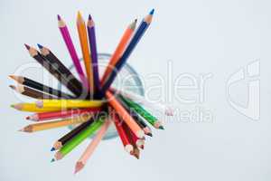 Colored pencils kept in glass on white background
