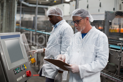 Two factory engineers operating machine in factory