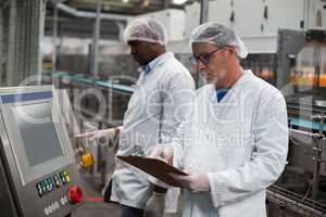 Two factory engineers operating machine in factory