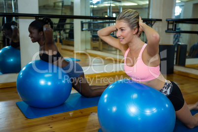 Two smiling women performing pilate on exercise ball