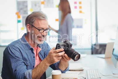 Male graphic designer looking at pictures on digital camera