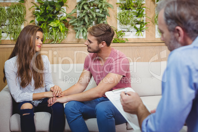 Couple holding hands while consulting doctor