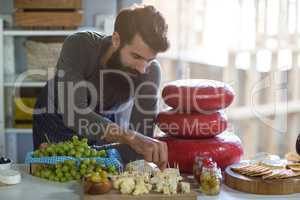 Salesman arranging cheese at counter