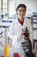 Portrait of schoolgirl experimenting on microscope in laboratory