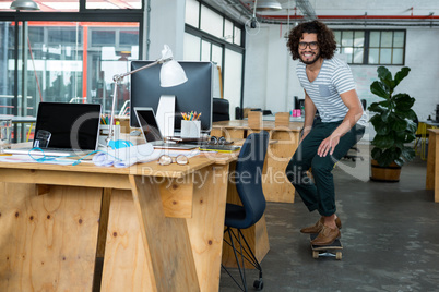 Graphic designer skating with skateboard in creative office