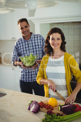 Smiling couple chopping vegetables in the kitchen at home