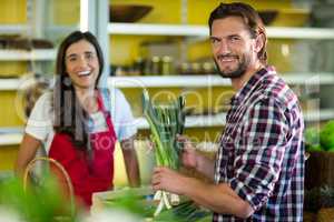 Smiling man holding a bunch of spring onions in the grocery store