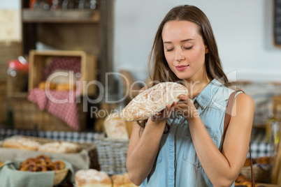 Smiling woman smelling a round loaf of bread at counter