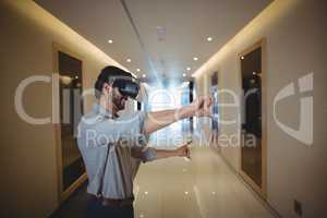 Male executive using virtual reality headset in corridor