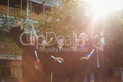 Successful graduate school kids throwing mortarboard in air in campus