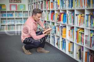 Attentive school teacher selecting book in library