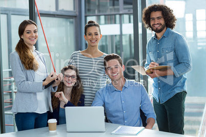 Portrait of smiling business team discussing over laptop in meeting