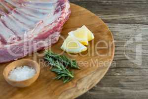 Beef ribs rack, rosemary herb, salt and lemon on wooden tray against wooden background