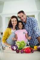 Portrait of parents and daughter preparing salad in kitchen